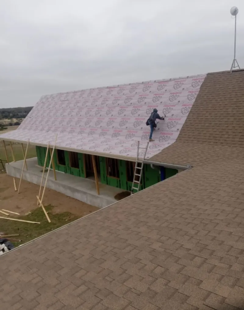 Worker preparing underlayment for a metal roof installation in Cypress